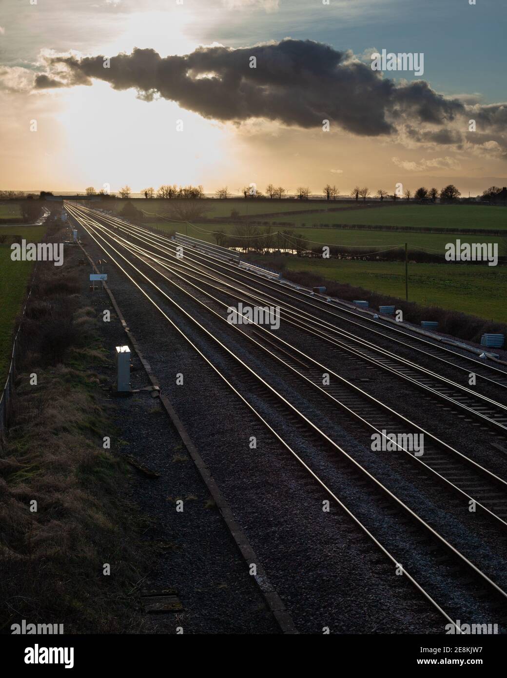 Vista serale delle piste ferroviarie della costa orientale Linea principale nello Yorkshire con luce solare dorata che si riflette rotaie Foto Stock