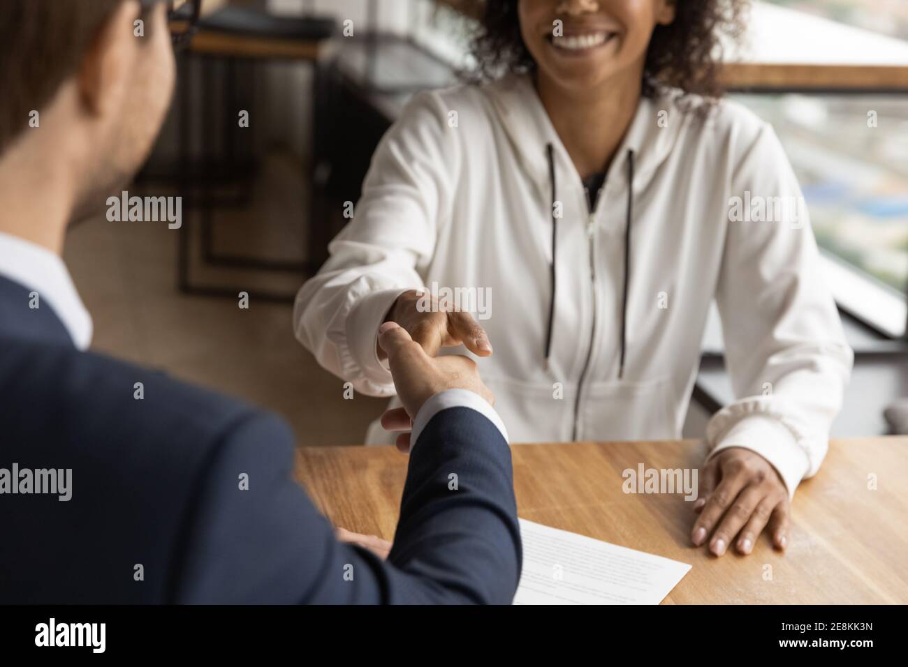 Sorridente donna africana handshaking familiarizzare con il giovane realtor maschile Foto Stock