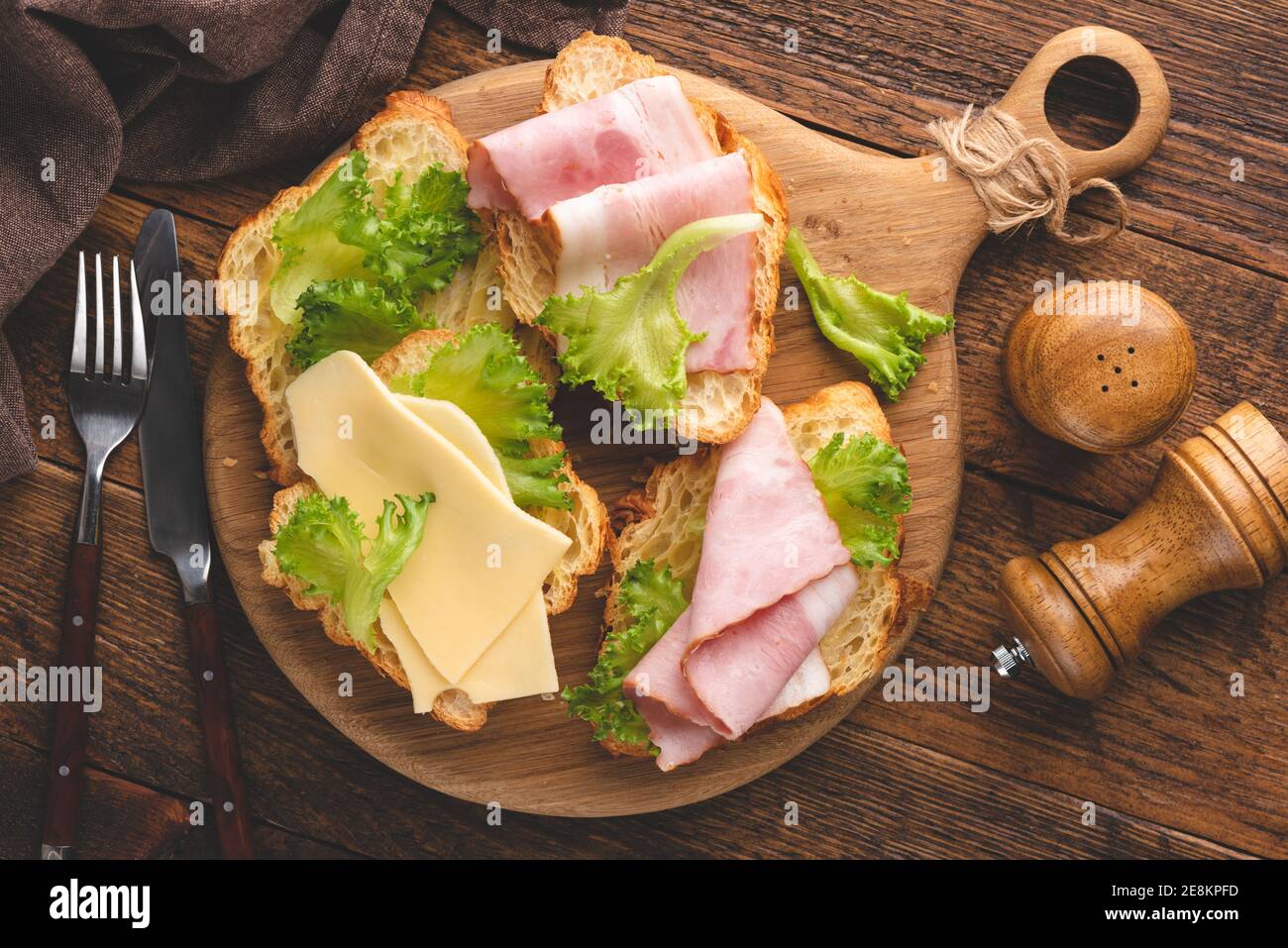 Panini con prosciutto di tacchino, formaggio e lattuga su un tagliere di legno. Vista dall'alto Foto Stock