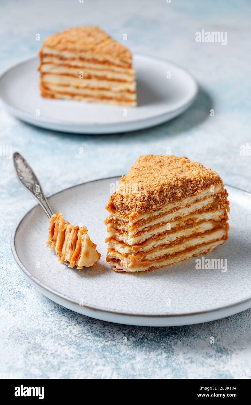 Pezzo di torta di Puff fatta in casa con latte condensato bollito sulla piastra su sfondo chiaro. Foto Stock