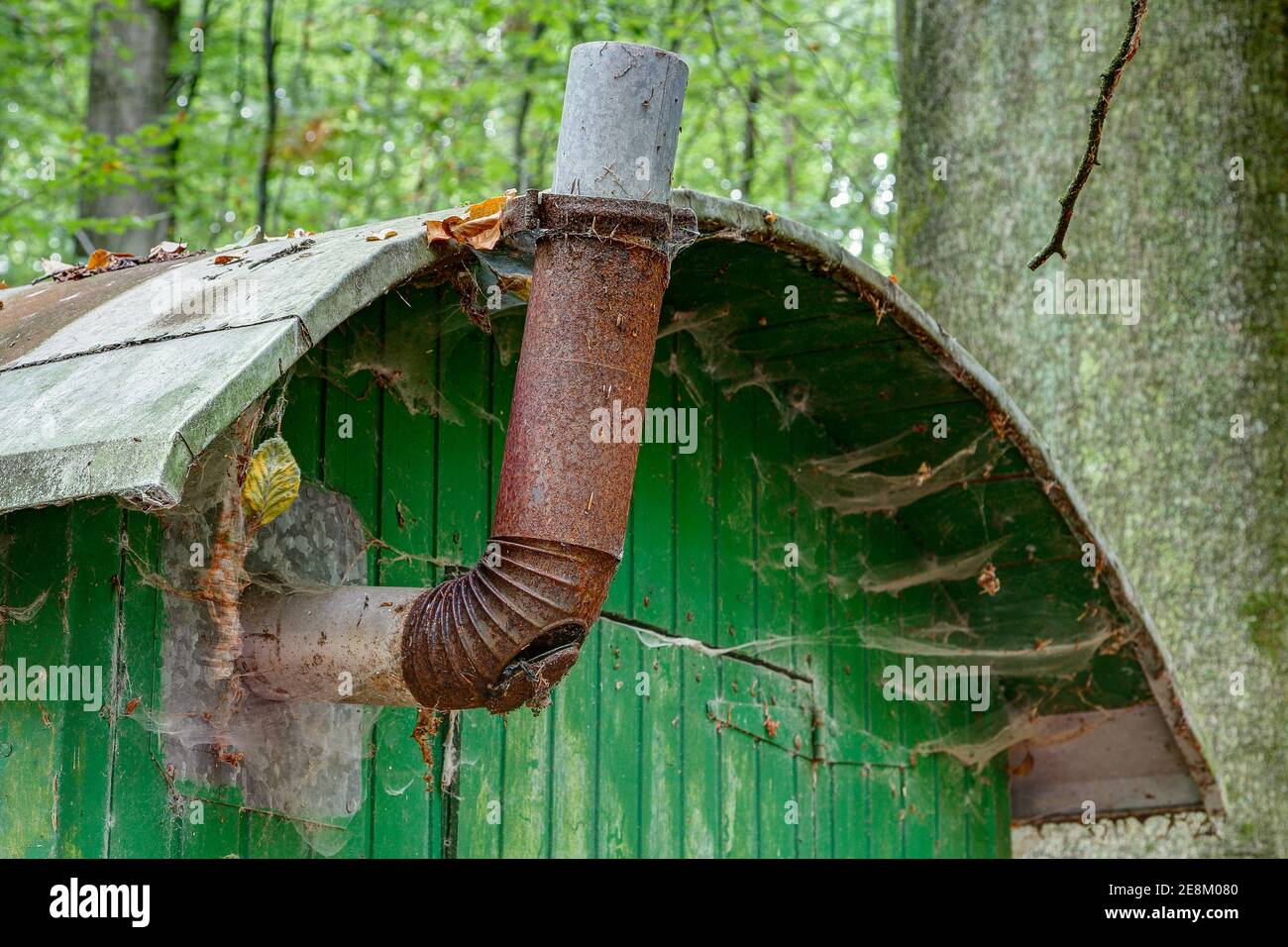 Vecchia stovepipe in metallo arrugginito e ciottoli sotto il tetto di latta su una carovana di protezione contro le intemperie per i lavoratori forestali. Foto Stock