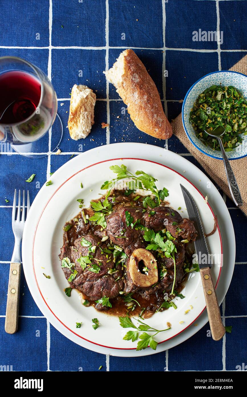 Ossobuco alla milanese vestito con gremolata su un tavolo di una trattoria tradizionale. Cucina italiana. Foto Stock