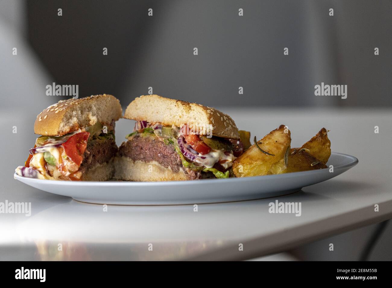 Un hamburger piatto in due metà servito con patate fritte Foto Stock