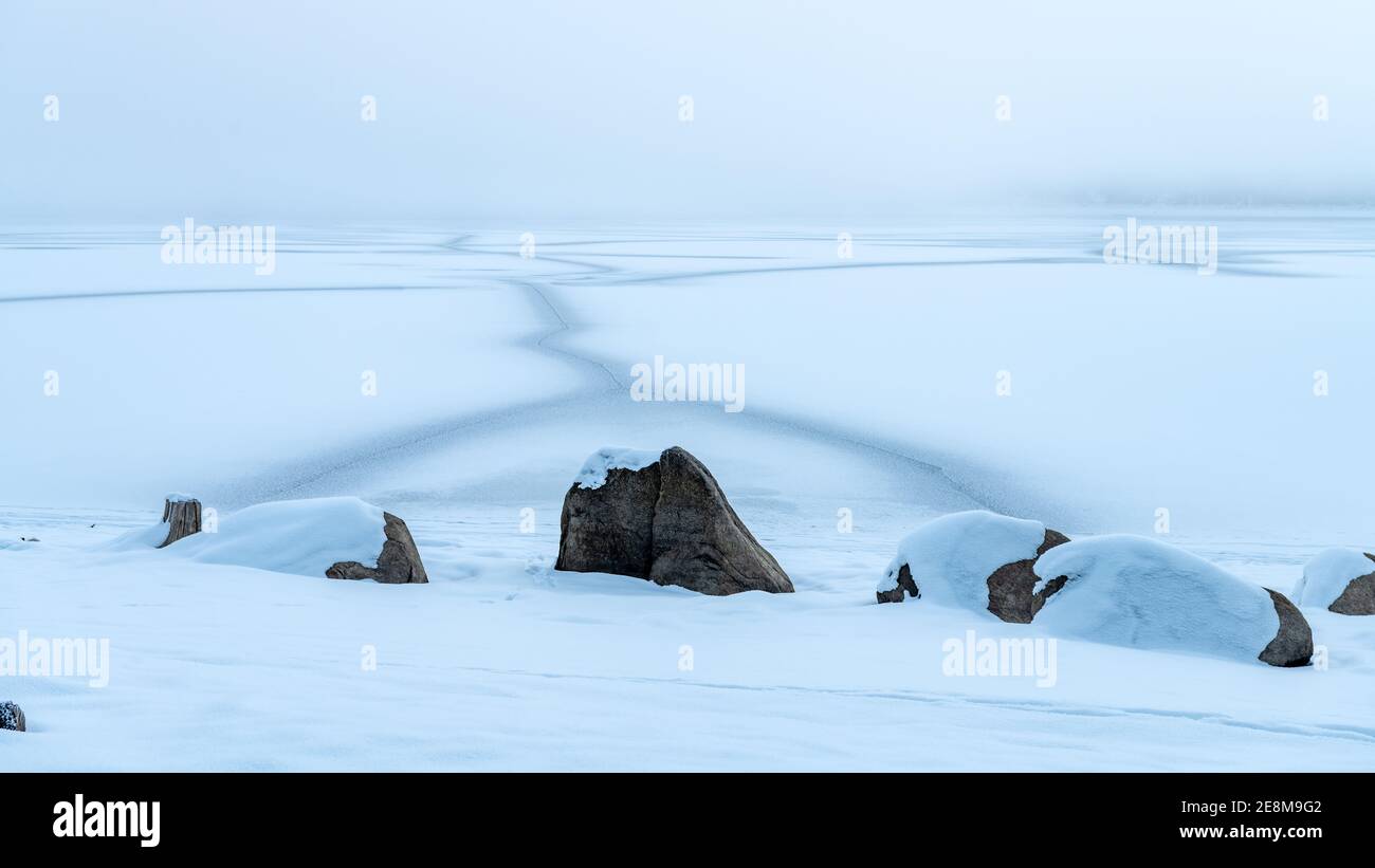 Rocce scure e ghiaccio del lago con crepe Foto Stock