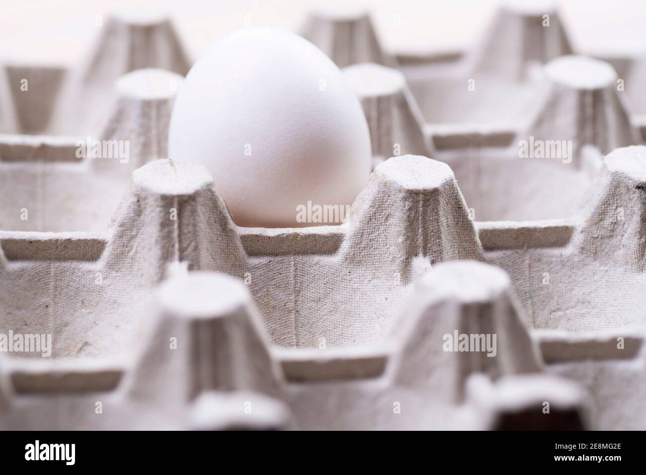 Scatola di cartone per uova crude con un primo piano per uova. Scatola di uovo grigia. Contenitore di carta di scarto per l'imballaggio delle uova grezze. Materiale di imballaggio. Scatola delle uova. Foto Stock