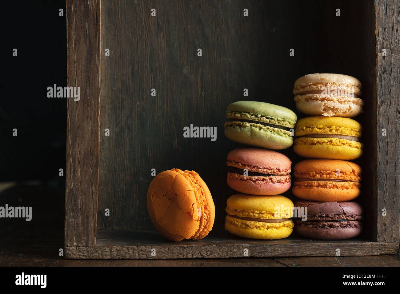 Pila di classici deliziosi macaron o macaron in un cassetto scuro di una vecchia sponda, primo piano Foto Stock
