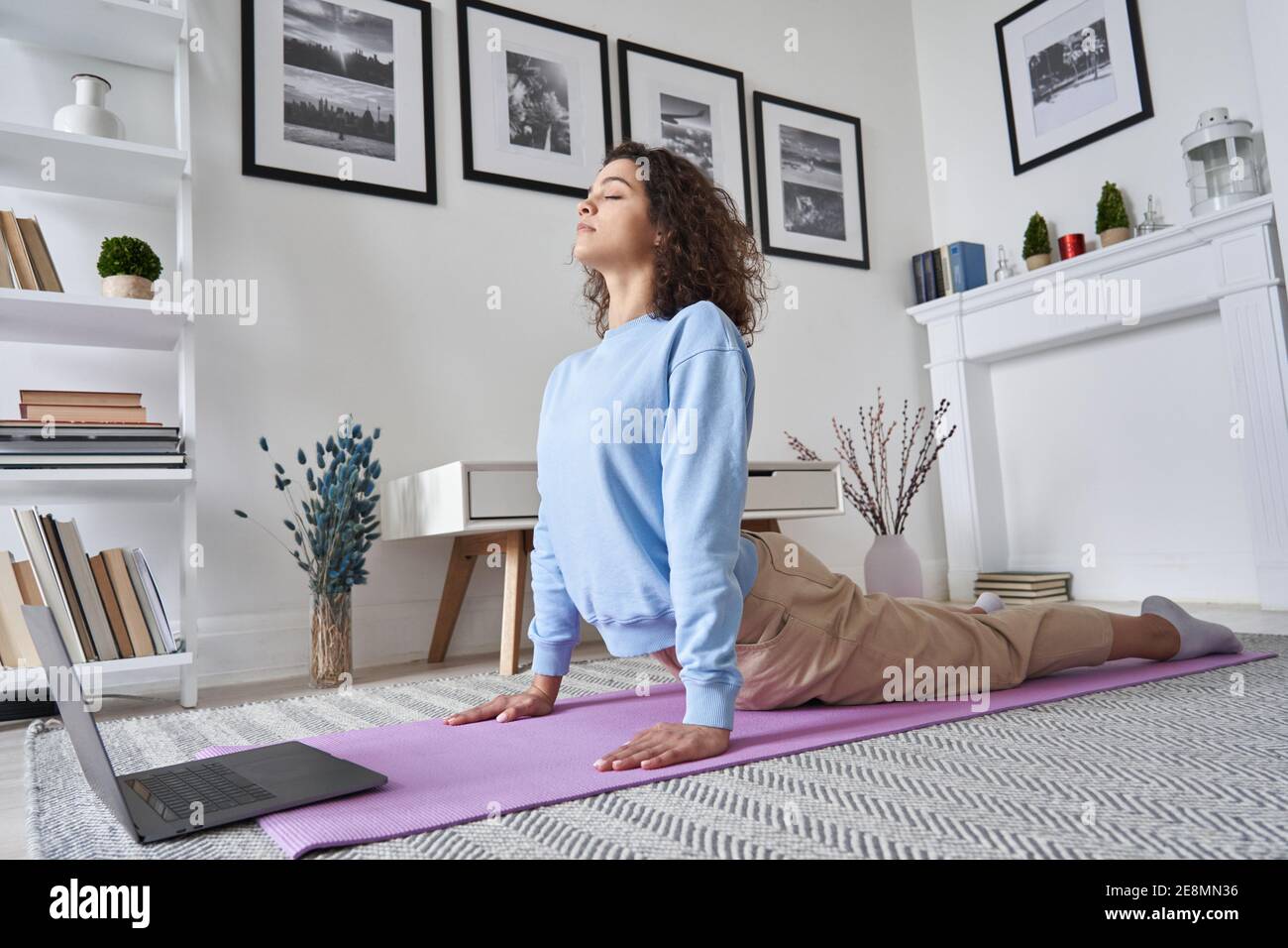 Fit giovane donna facendo yoga stretching esercizio guardando classe online sul computer portatile. Foto Stock