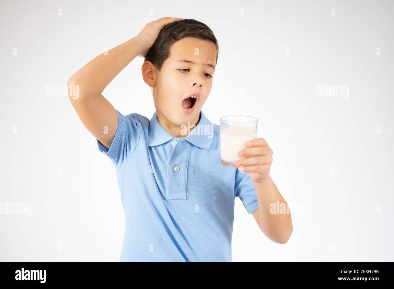 ute ragazzo in camicia blu con un bicchiere di latte sfondo bianco Foto Stock