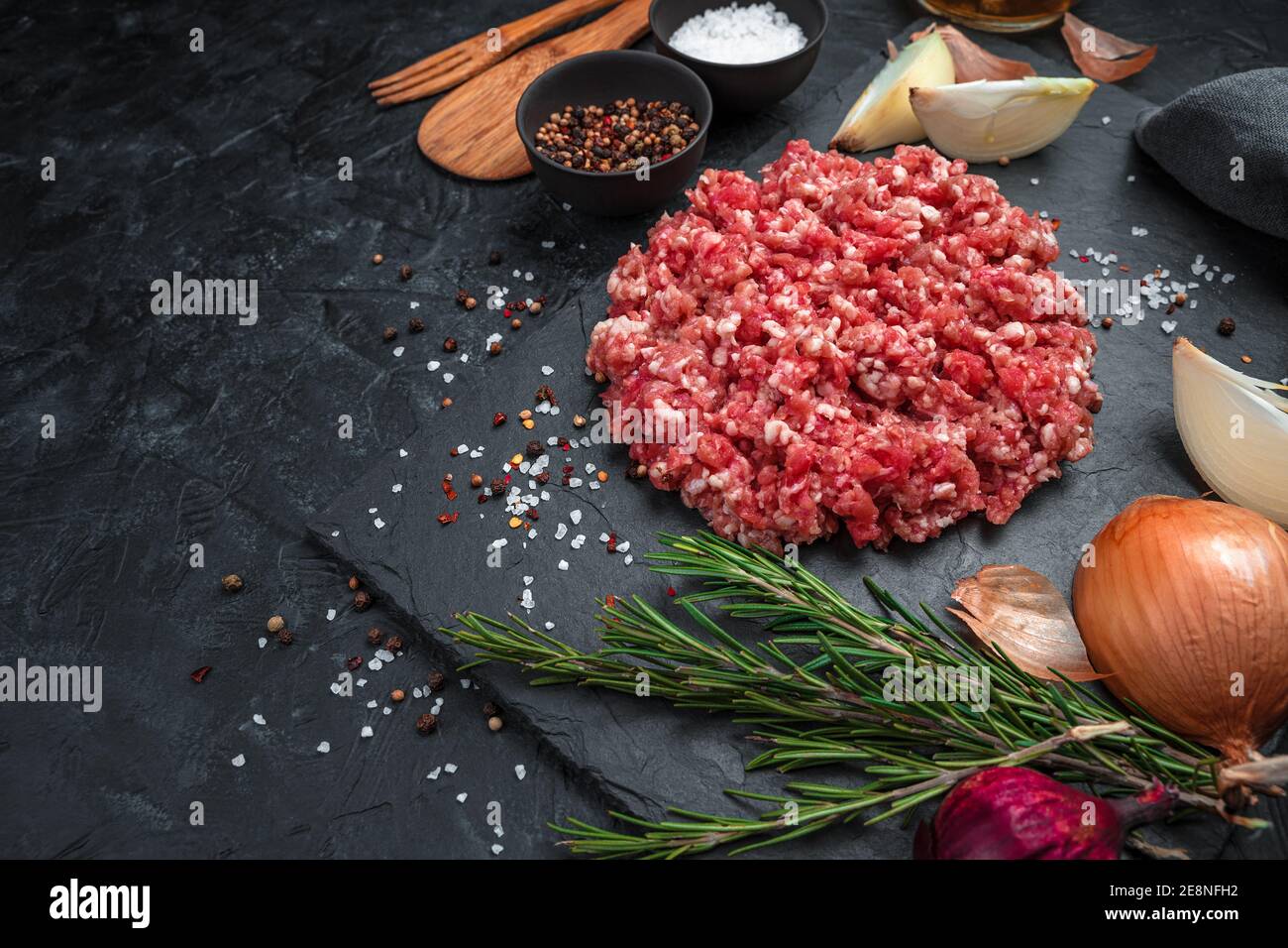 Carne sminuzzata fresca e succosa con spezie su un piatto piatto su fondo nero. Foto Stock