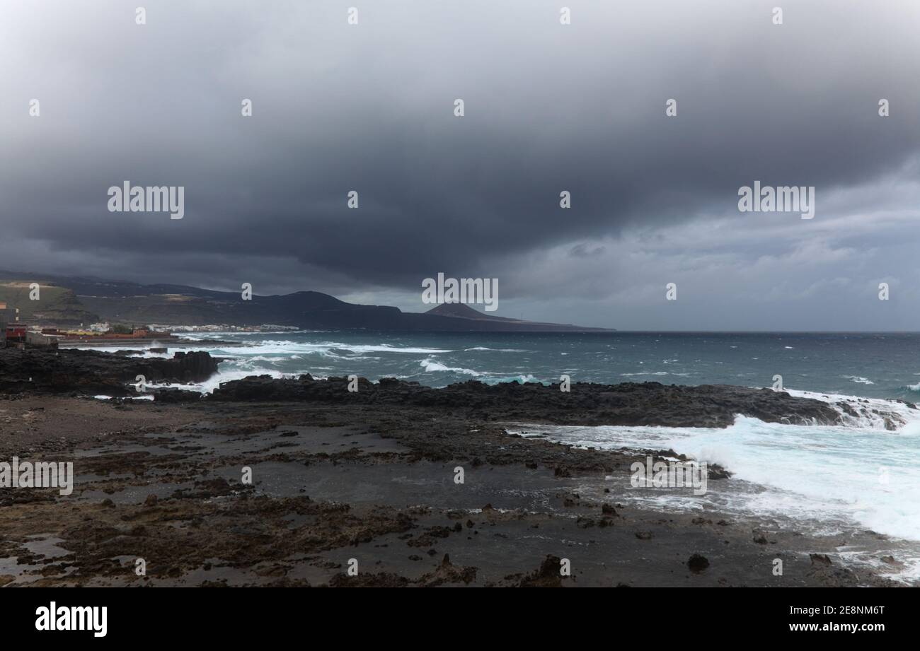 Gran Canaria, vista verso il corpo principale dell'isola dalla spiaggia di El Confital al limitare di Las Palmas de Gran Canaria, pioggia che attraversa l'isl Foto Stock