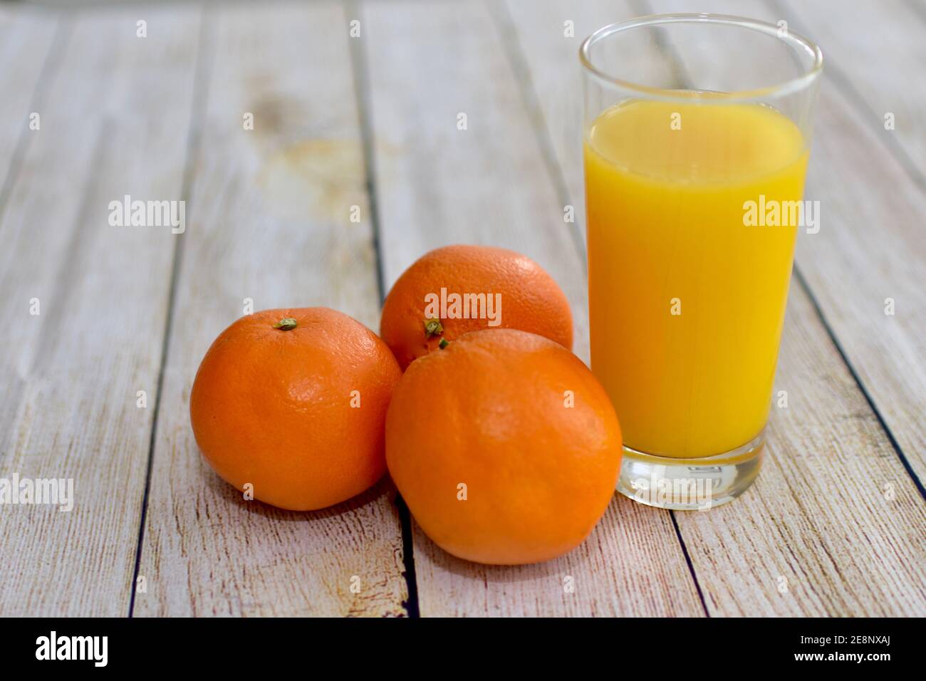 Fresco spremuto sano succo d'arancia e intere arance ombelico primo piano sfondo, concetto foto vita sana, spazio copia Foto Stock