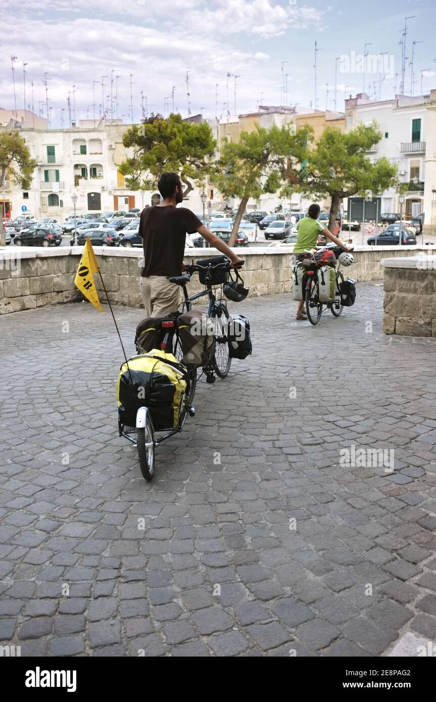 Bari, Italia - 08 luglio 2013: Due giovani ciclisti, maschili e femminili, portano fuori dal castello normanno-svevo di Bari le loro biciclette, una delle quali è e. Foto Stock