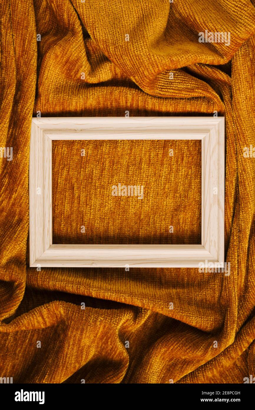 Concetto creativo di cornice in legno bianco su tessuto giallo dorato tessuto onda sfondo. Design minimo con spazio di copia. Foto Stock