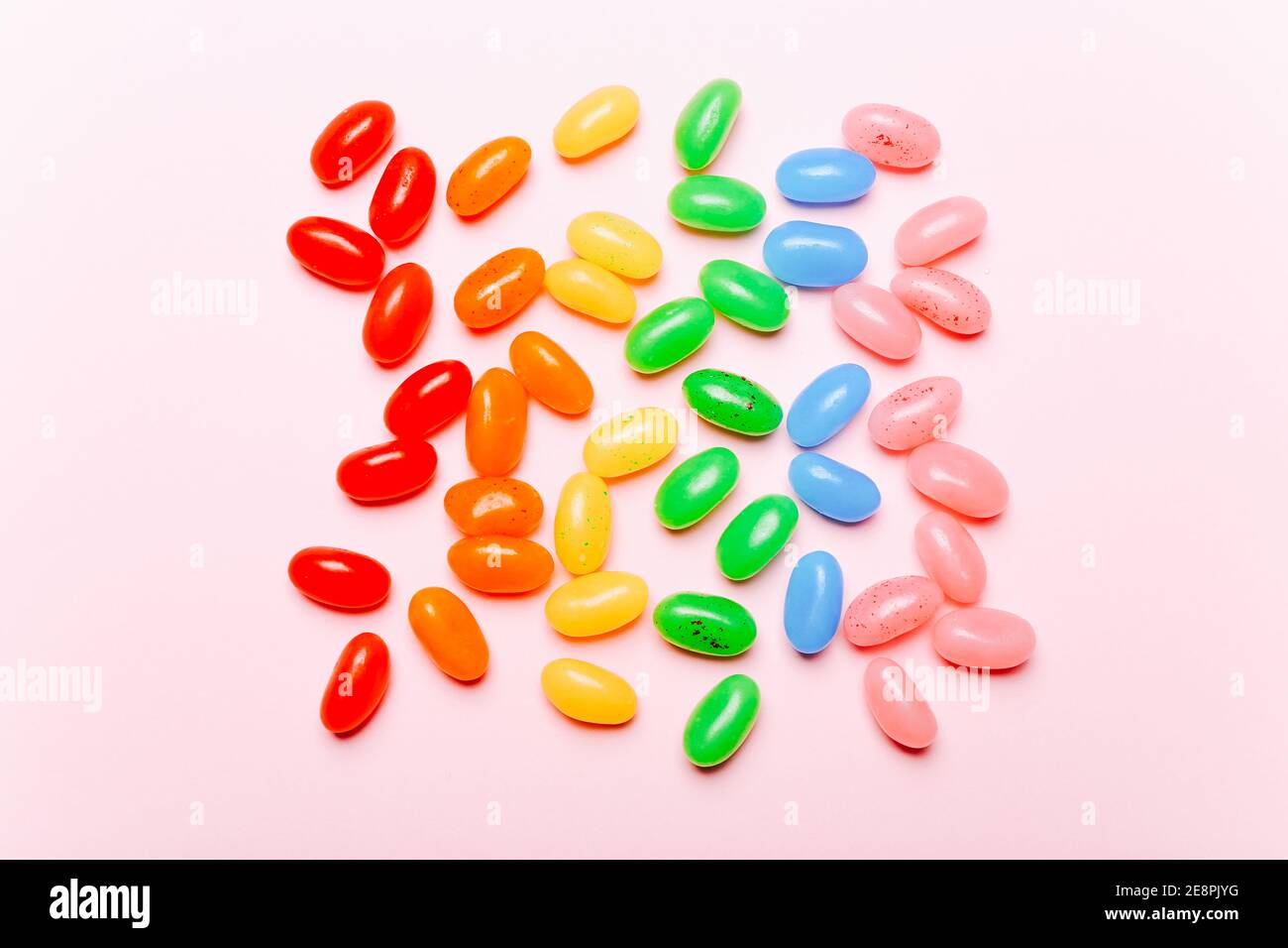 Fagioli di gelatina di arcobaleno dolce su sfondo rosa. Vista dall'alto Foto Stock
