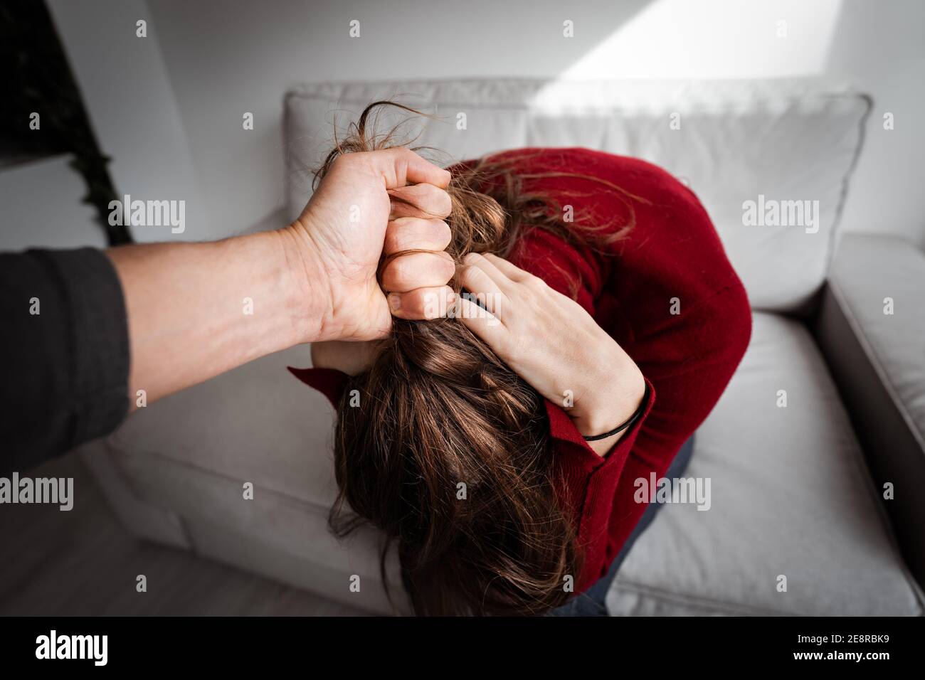 Uomo che batte donna indifesa a casa. Vittima di violenza domestica. Donna nella paura. Violenza contro la donna Foto Stock