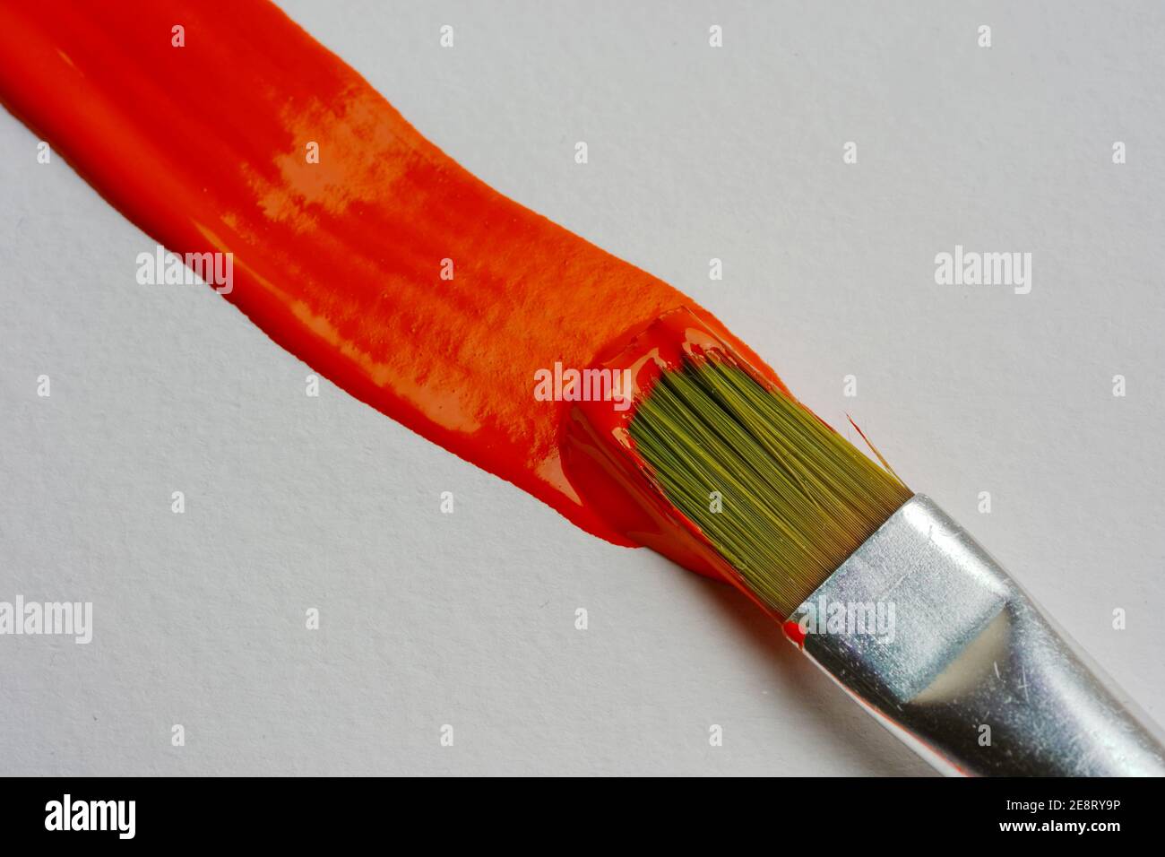 Pennello applica una linea arancione alla carta, primo piano Foto Stock