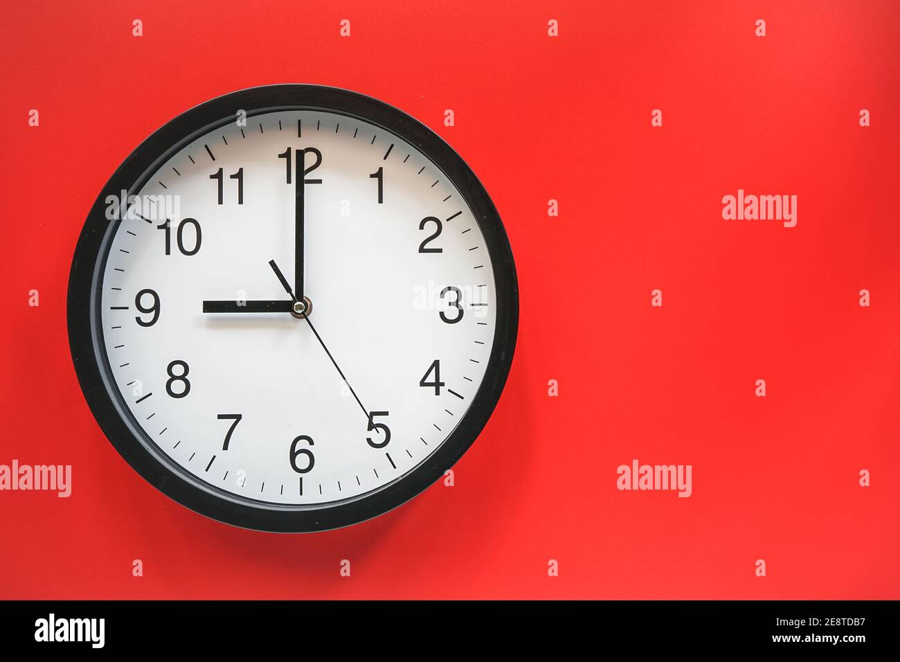 Orologio analogico classico in bianco e nero su sfondo rosso a. Ore nove con spazio per la copia Foto Stock