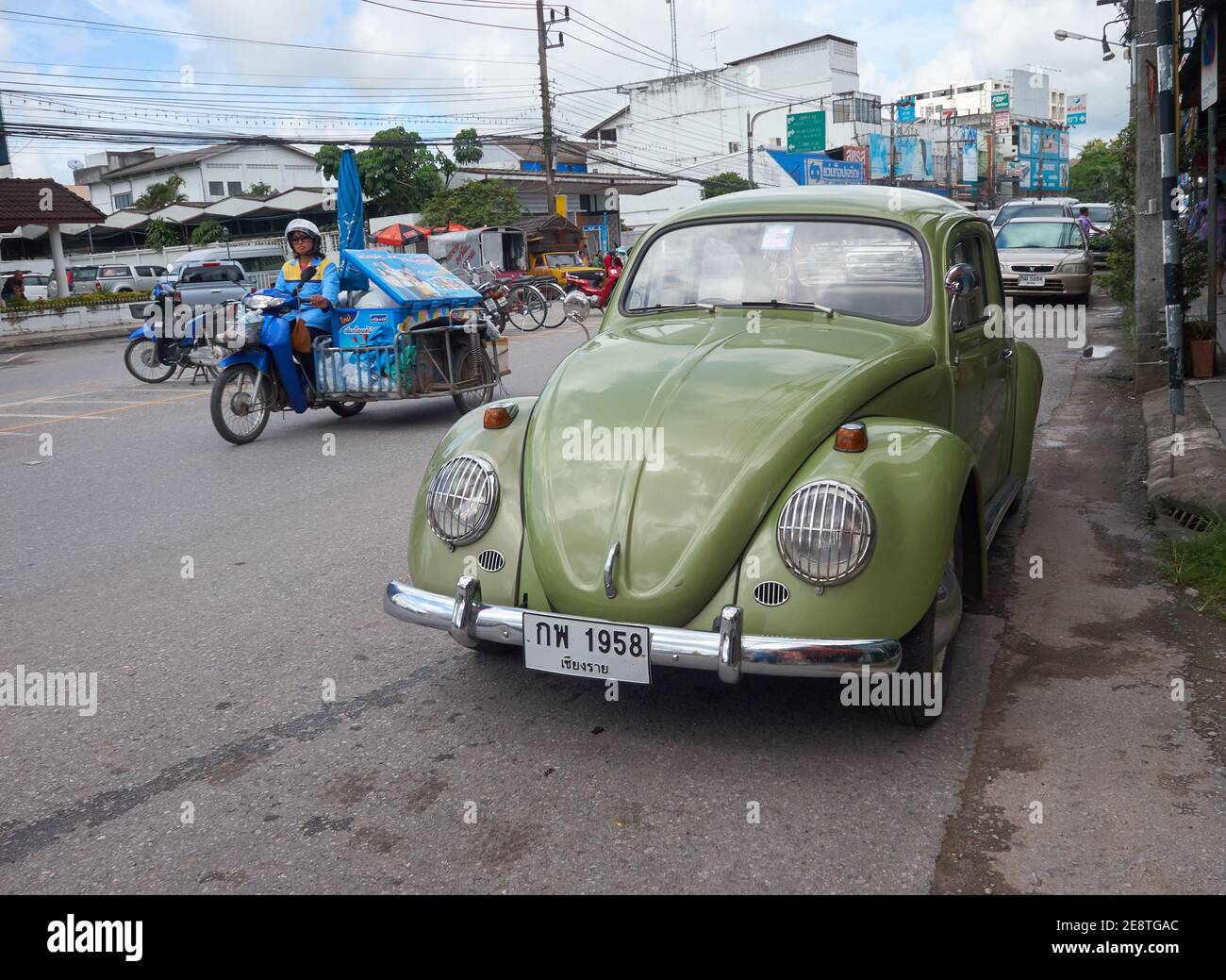Un scarabeo volkswagen verde è parcheggiato sul lato di la strada sullo sfondo di una moto in marcia Foto Stock
