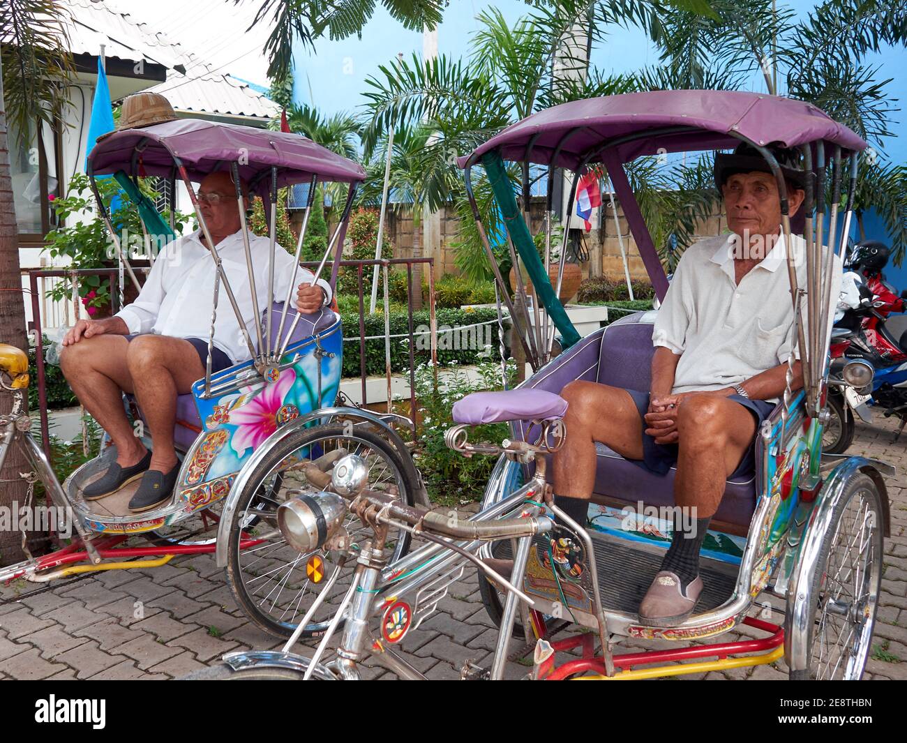 Due uomini di mezza età che guidano risciò, seduti nel risciò in attesa dell'arrivo dei passeggeri che utilizzeranno i loro servizi Foto Stock