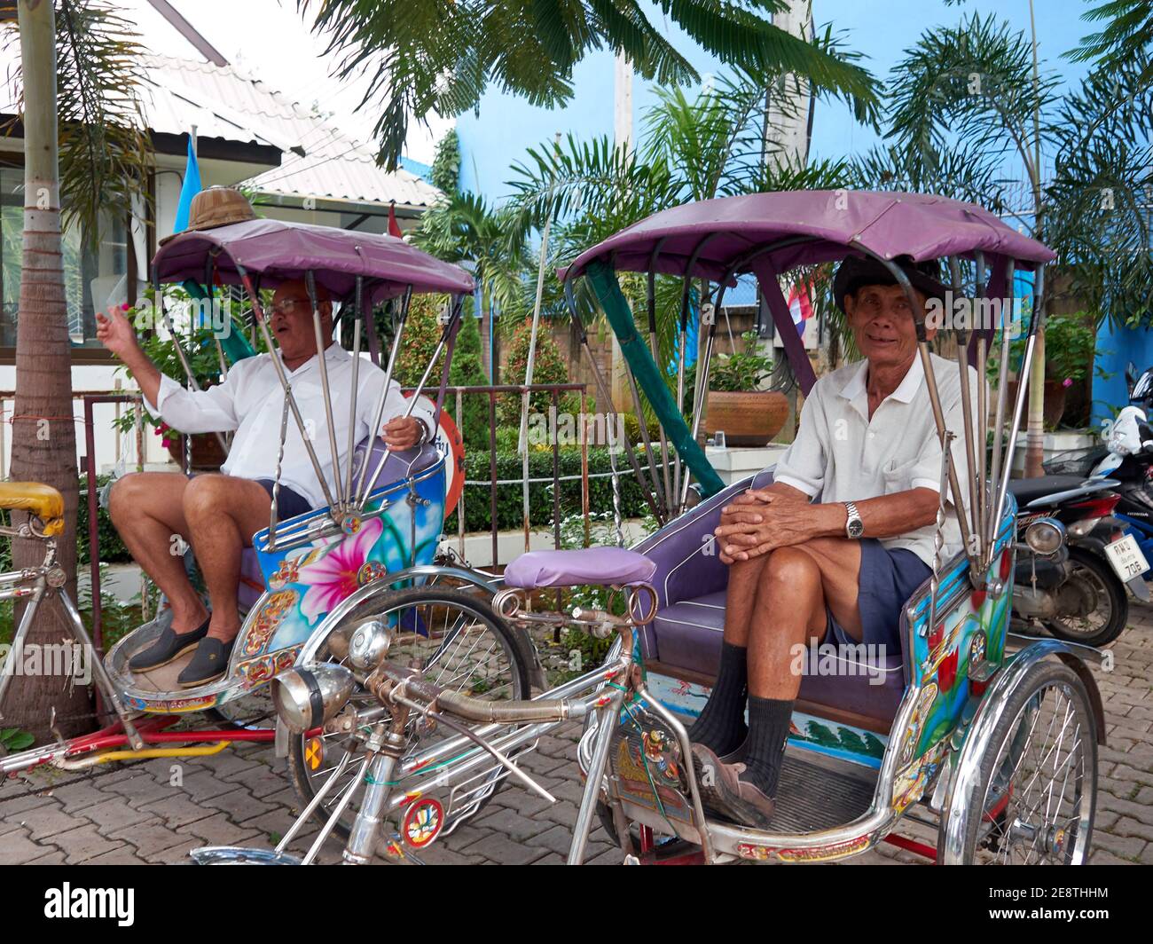 Due piloti pedicab maschi si siedono casualmente nei loro risciò in attesa per l'arrivo di passeggeri che utilizzeranno i loro servizi Foto Stock