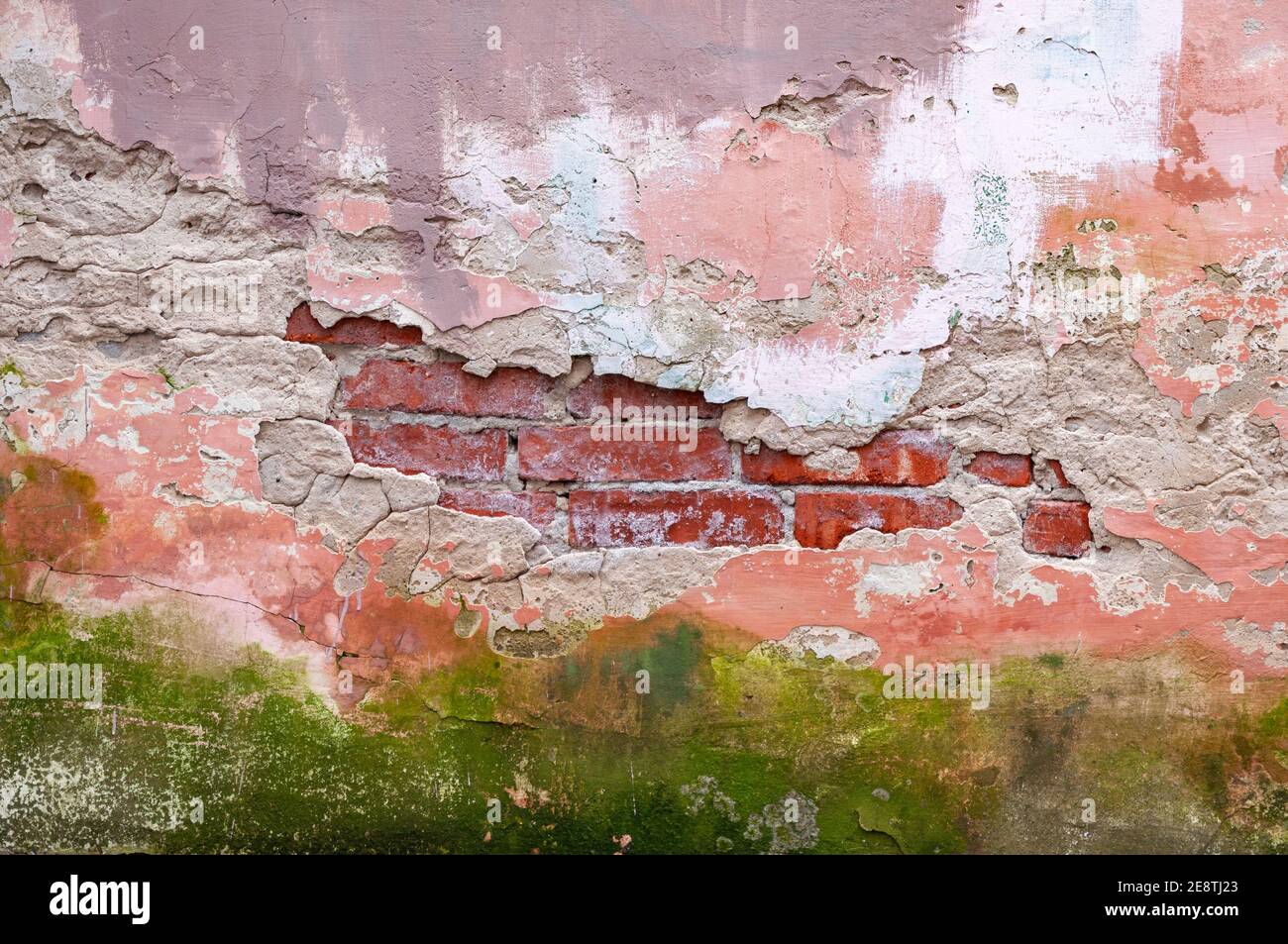 Il muro di mattoni di un vecchio edificio con intonaco rovinato. Foto Stock