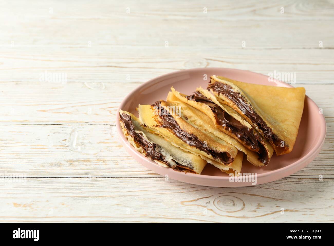Piatto di crepes con pasta di cioccolato su sfondo bianco di legno Foto Stock