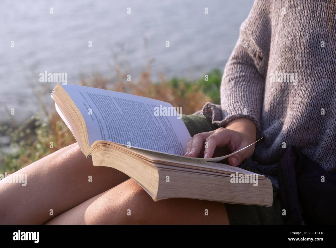 Giovane donna libro lettura mentre seduti all'aperto, vista da vicino Foto Stock