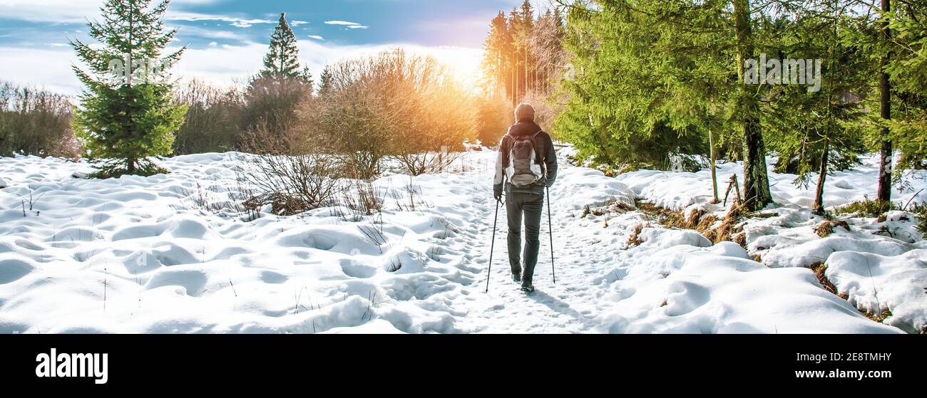 Escursione maschile escursionista con zaino e bastoni nordici nella neve. Foto Stock