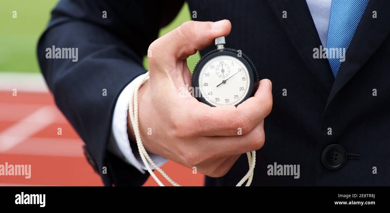 Il tempo è in esecuzione - l'uomo d'affari nello stadio tiene il cronometro dentro la sua mano - primo piano Foto Stock