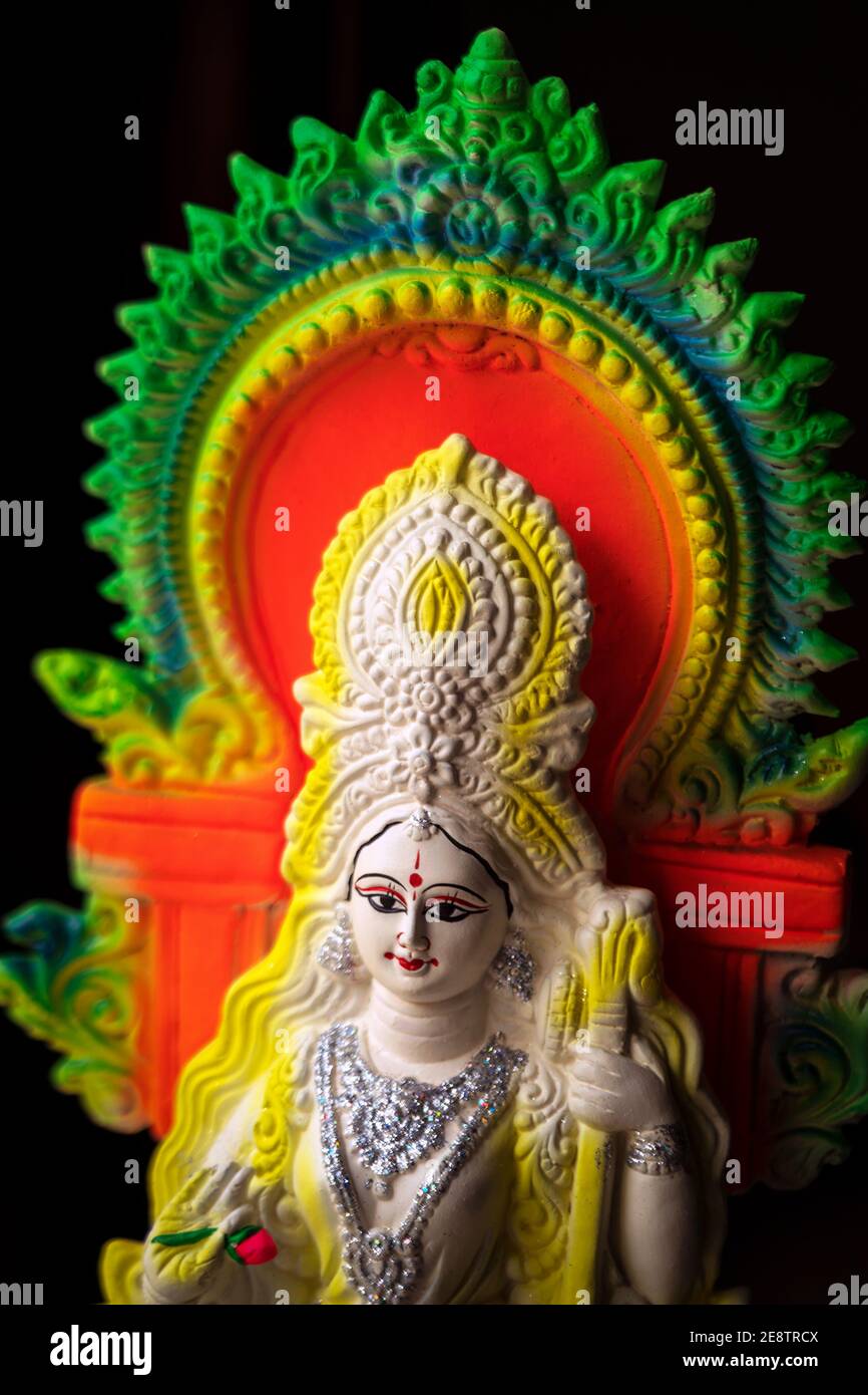 Vasant Panchami sfondo. Idolo argilloso colorato della Dea Saraswati che tiene una veena, isolato in nero. Rituale indù puja, cultura tradizione religiosa Foto Stock