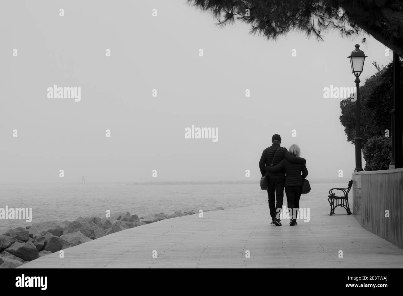 una sola coppia lungo il molo nella nebbia Foto Stock