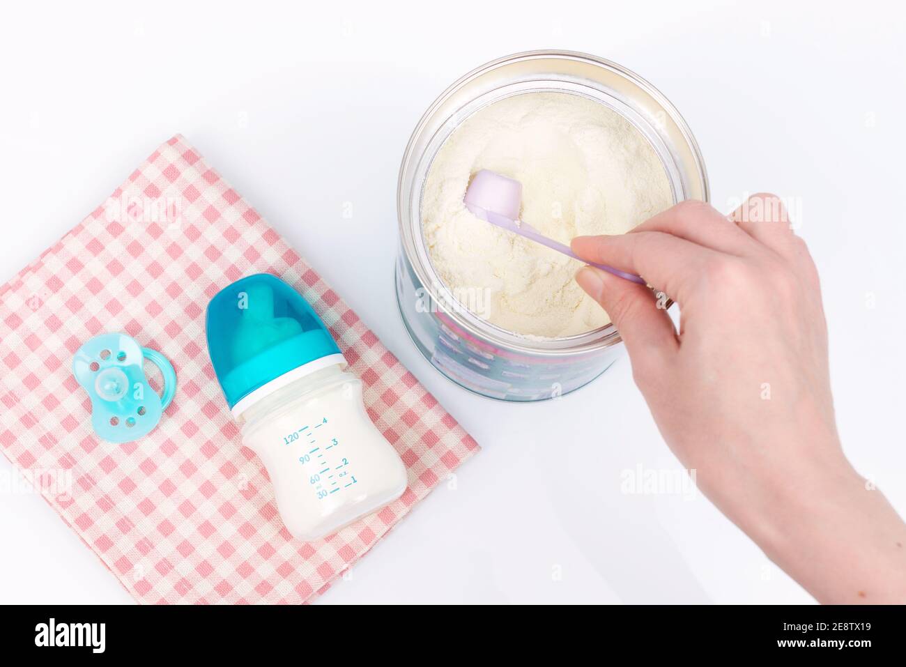 Mano della donna che afferra una paletta di latte del bambino in polvere.  Formula del latte per bambini e biberon Foto stock - Alamy