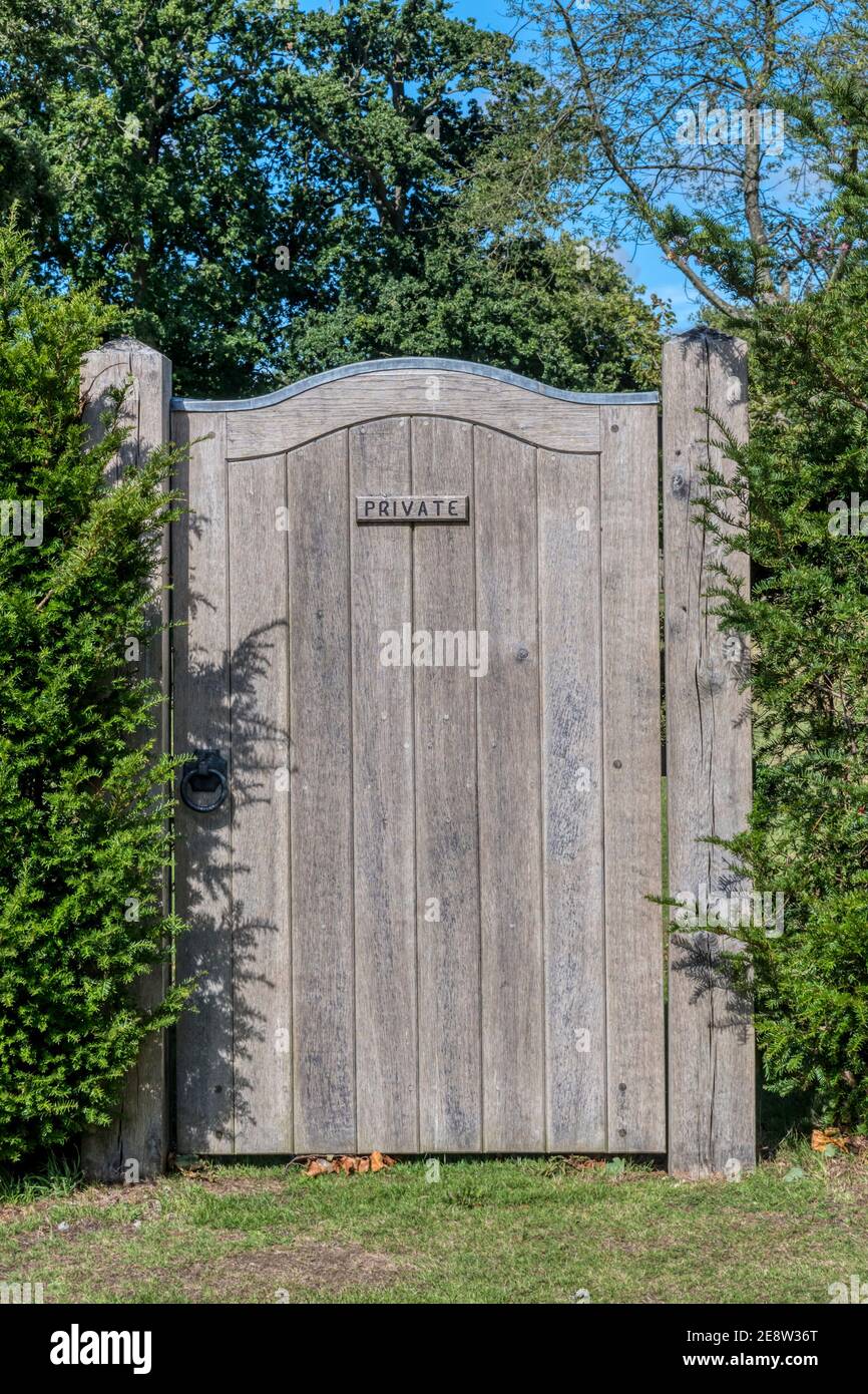 Un alto cancello di legno in una siepe di tasso, segnato privato. Foto Stock