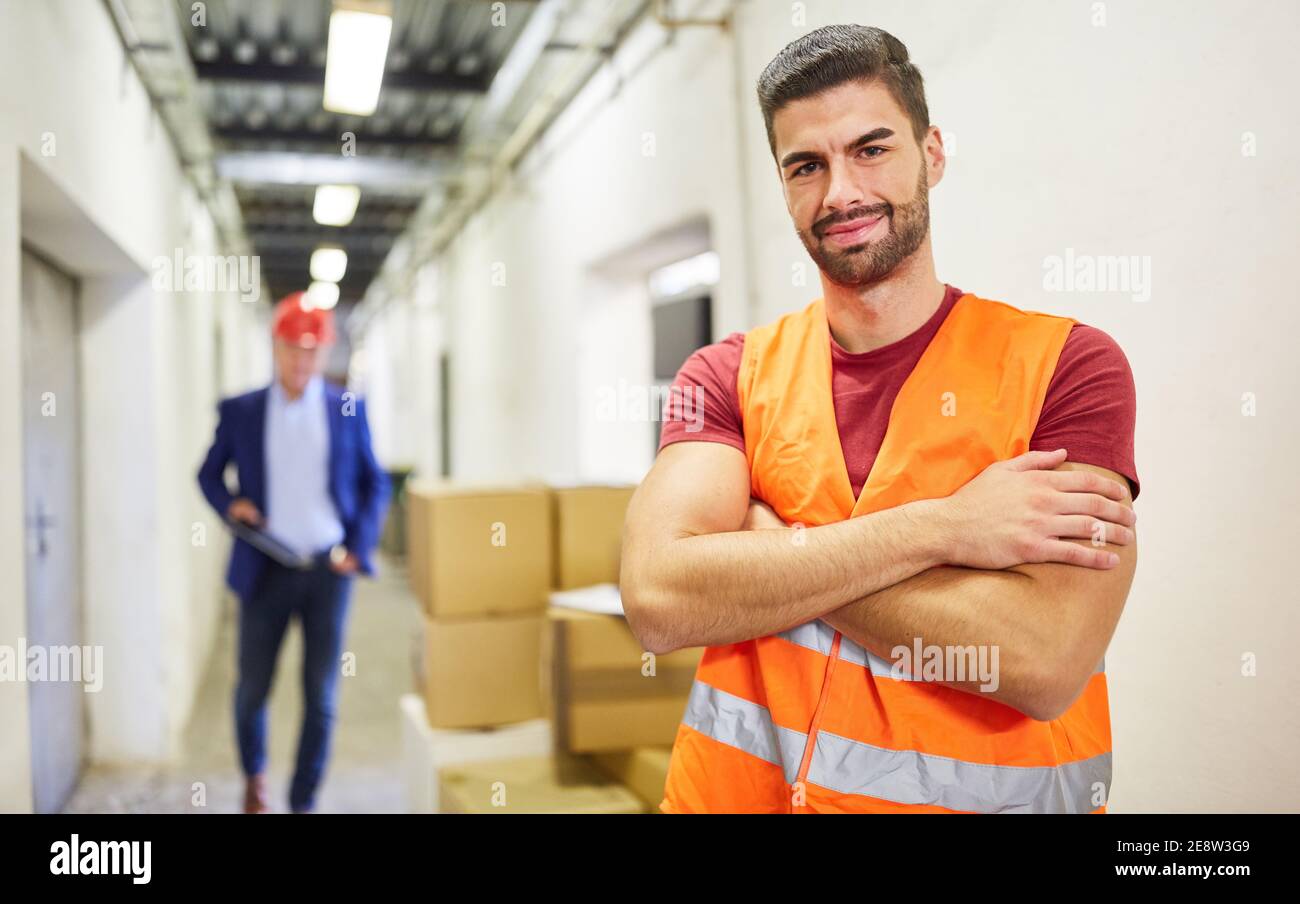 Lavoratore con giubbotto di sicurezza come impiegato di magazzino nel magazzino di una società di spedizione o nel reparto spedizioni Foto Stock