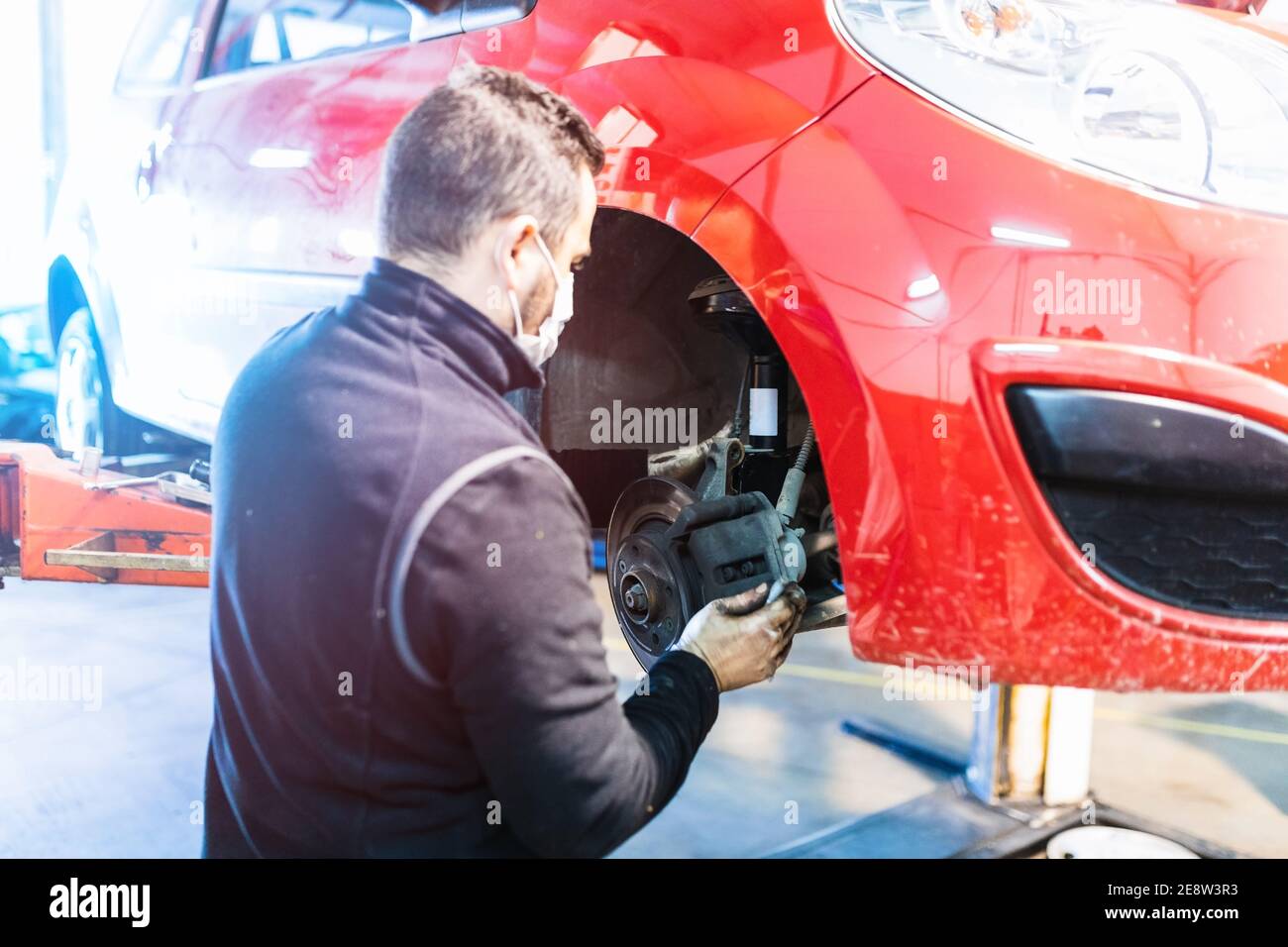 meccanico che ripara la sospensione dell'auto. Concentratevi sulle mani. COVID 19 Foto Stock