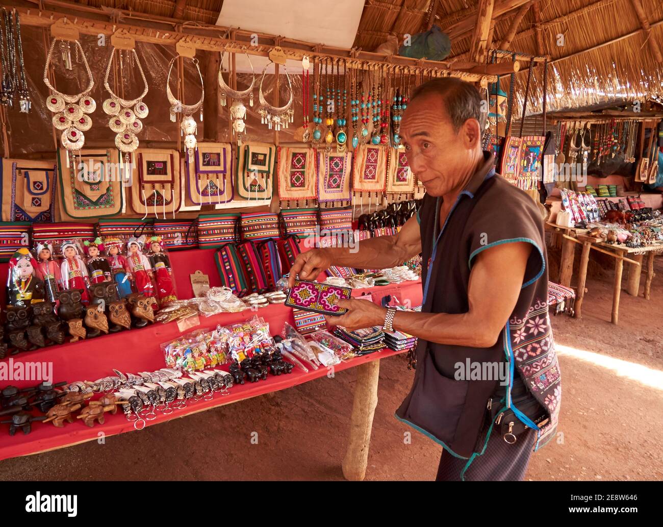 Un uomo della tribù di Akha sta offrendo la sua merce dentro la forma di artigianato Foto Stock