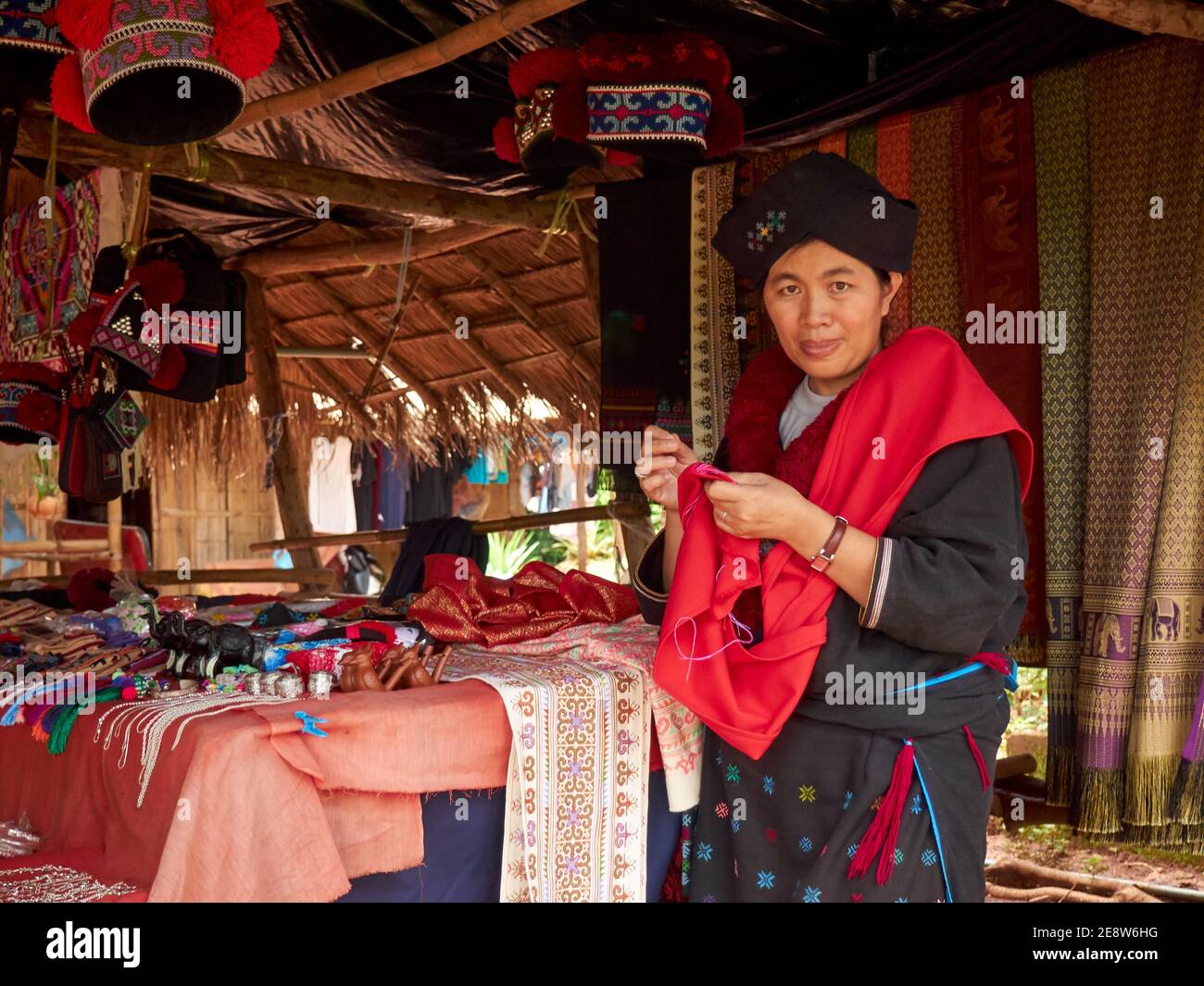 Ritratto di una donna della collina Mein o Yao Tribù che lavora ricamo abiti tradizionali in attesa della sua merce acquirenti Foto Stock