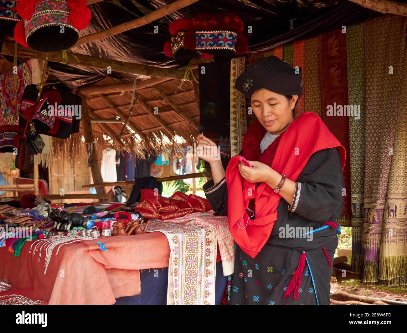 Una donna dei ricami di Mein o Yao Hill Tribe vestiti tradizionali mentre attende i suoi compratori di merce Foto Stock