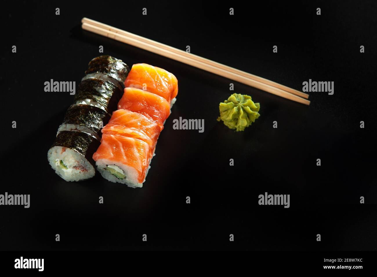 Rotolo di sushi personalizzato in tempura con nori, salmone fresco, tonno, avocado, caviale di masago, condito con salsa di ananas e insalata da versare come decorazione Foto Stock