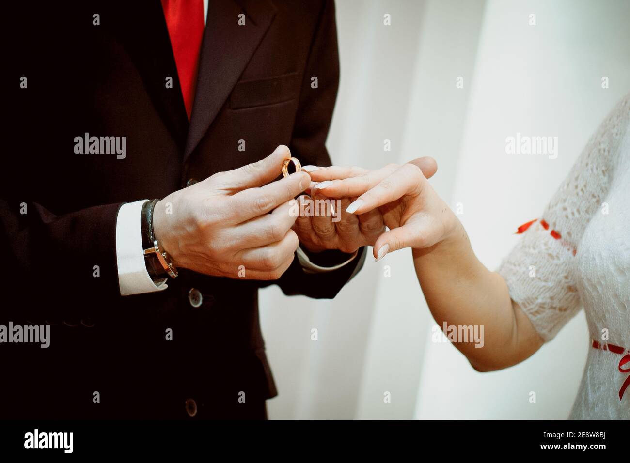 Lo sposo mette l'anello sulla sposa la mano. Le mani degli sposi che il giorno del matrimonio, close-up. Lo scambio degli anelli durante il matrimonio. Foto Stock