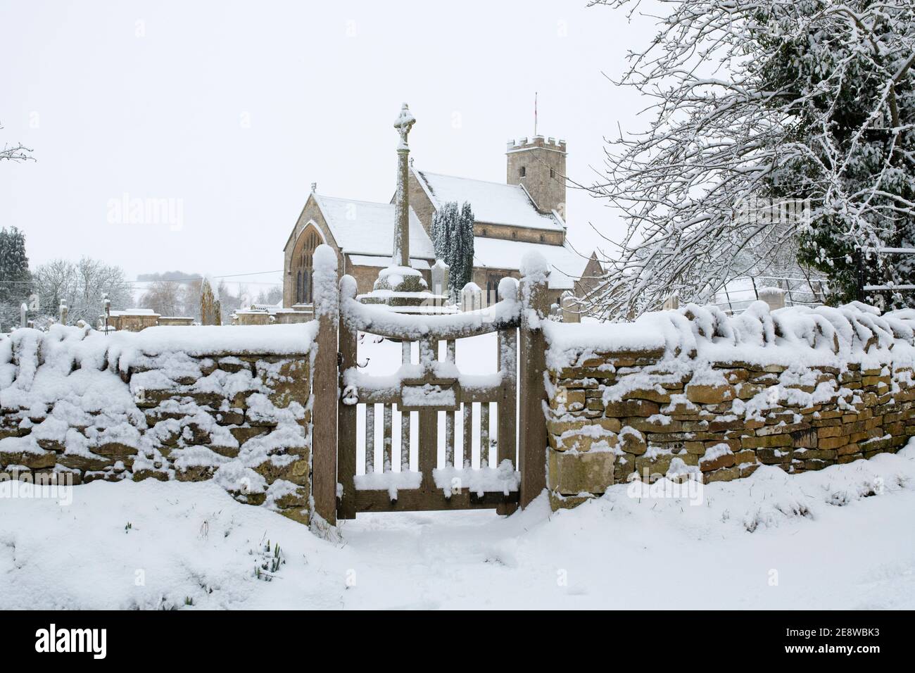 Chiesa di San Marys e porta nella neve. Swinbrook, Cotswolds, Oxfordshire, Inghilterra Foto Stock