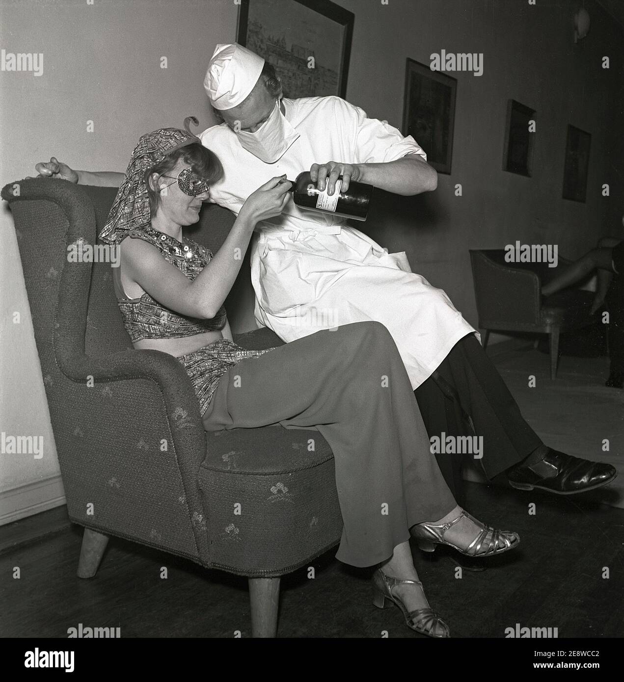 Masquerade negli anni '40. Un uomo vestito da chirurgo medico offre una signora harem una bevanda da una bottiglia della farmacia. Svezia 1945 Kristoffersson Rif L99-2 Foto Stock
