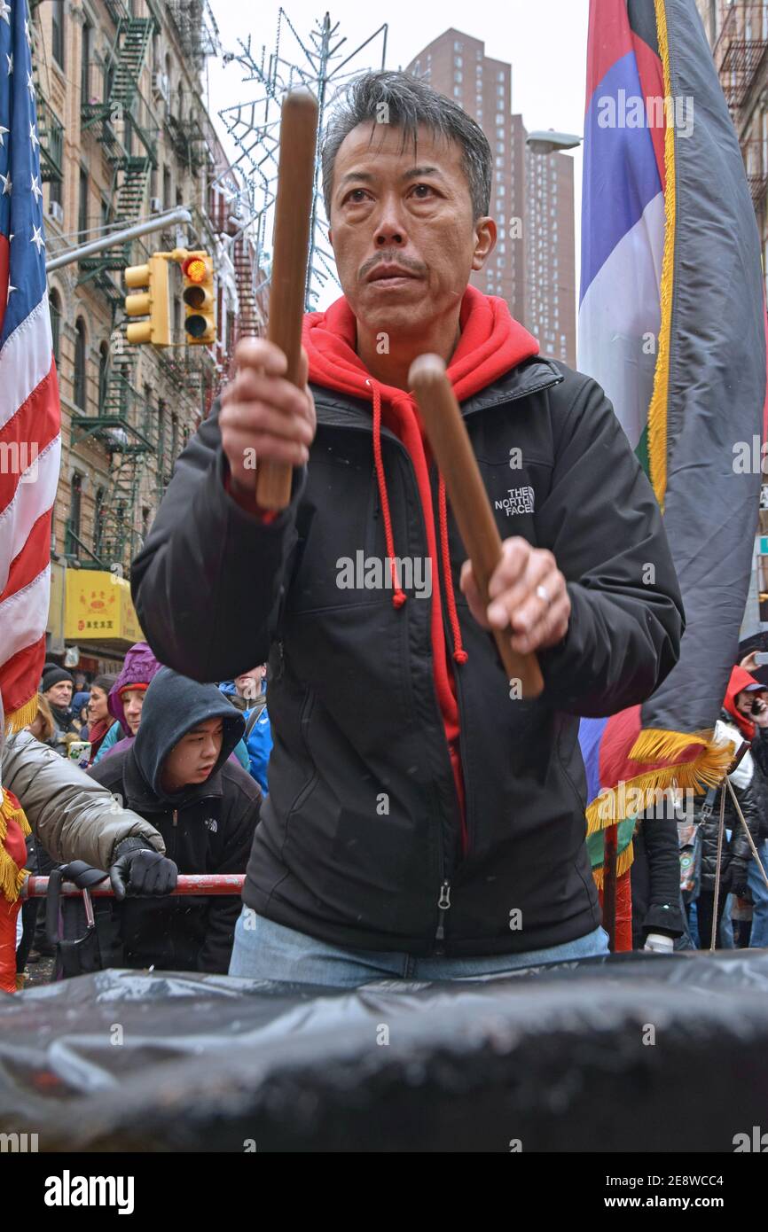 Un uomo cinese americano di mezza età suona la batteria durante le celebrazioni lunari di Capodanno a Chinatown, Manhattan nel 2016. Foto Stock