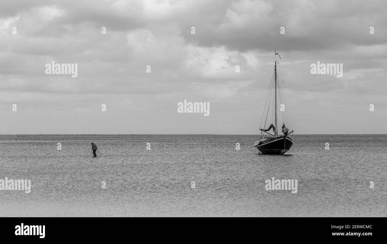 Barca a Vlieland. Queste navi a vela possono posare sulla sabbia a bassa acqua. Donna sta camminando dalla barca all'isola Foto Stock