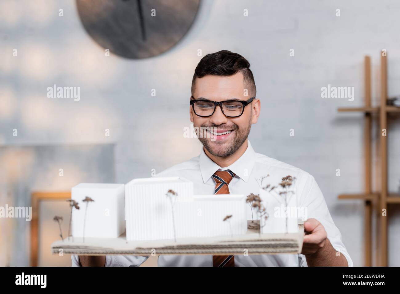 allegro architetto in occhiali che tiene gli edifici maquette in agenzia  architettonica Foto stock - Alamy