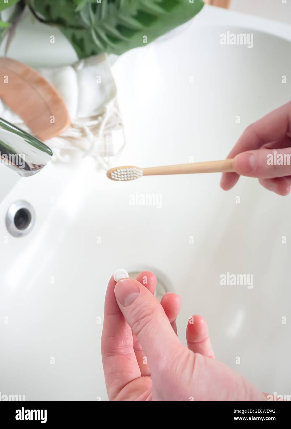 Mano caucasica che tiene una linguetta dentale eco-friendly come dentifricio e spazzolino di bambù. Uno stile di vita sostenibile con scambi di cura personale senza plastica. Foto Stock