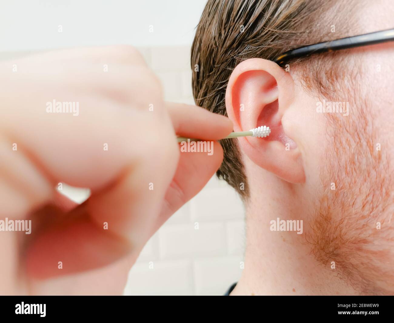Uomo che pulisce l'orecchio con un puntale riutilizzabile in silicone q-tip. Concetto di stile di vita senza sprechi. Foto Stock