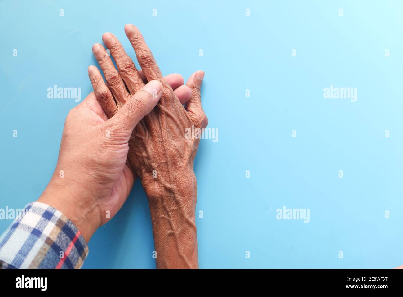 uomo che tiene la mano di una donna anziana su sfondo blu Foto Stock