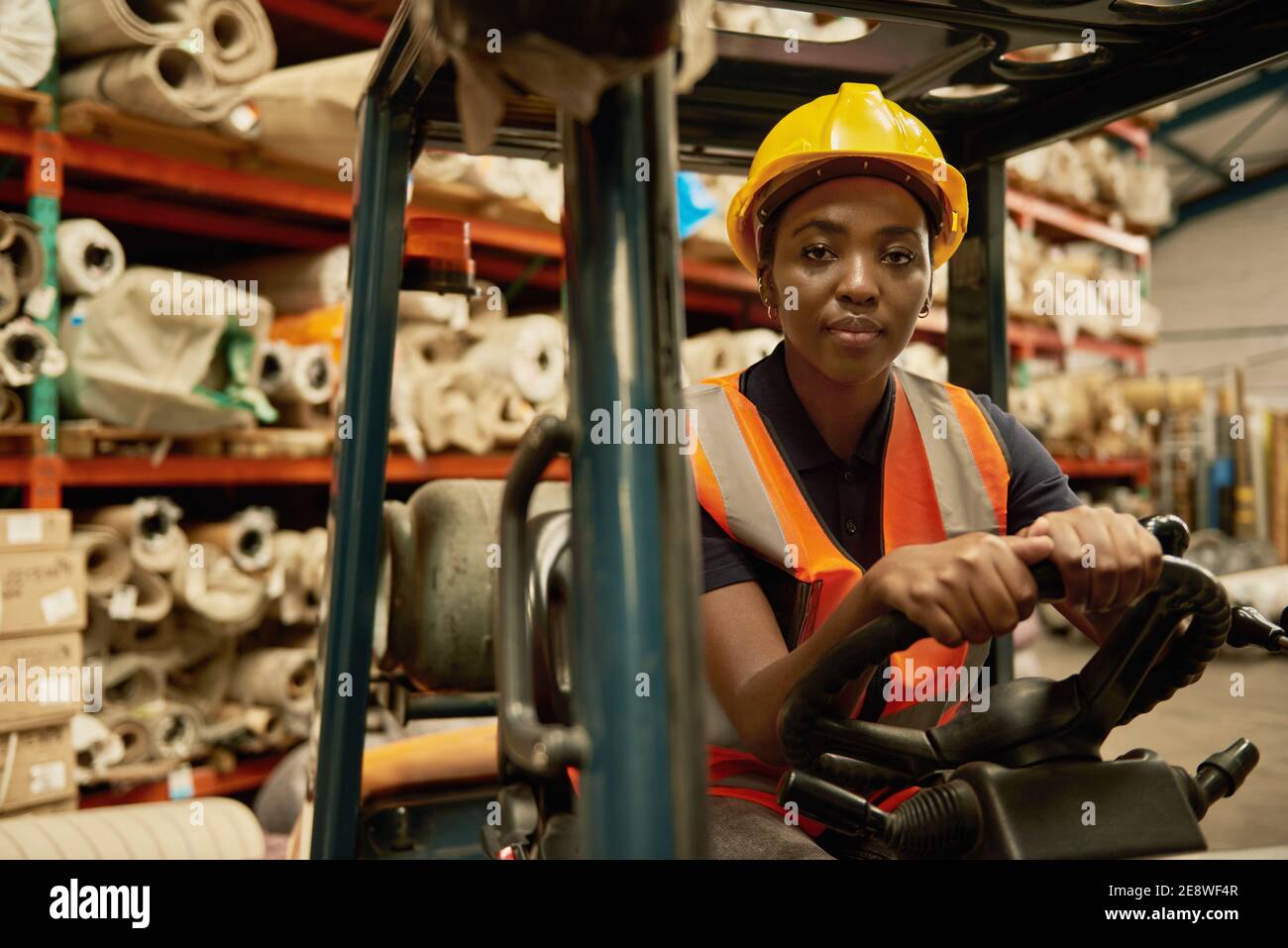 Fiducioso operatore africano di carrelli elevatori a forche che lavora in un magazzino Foto Stock