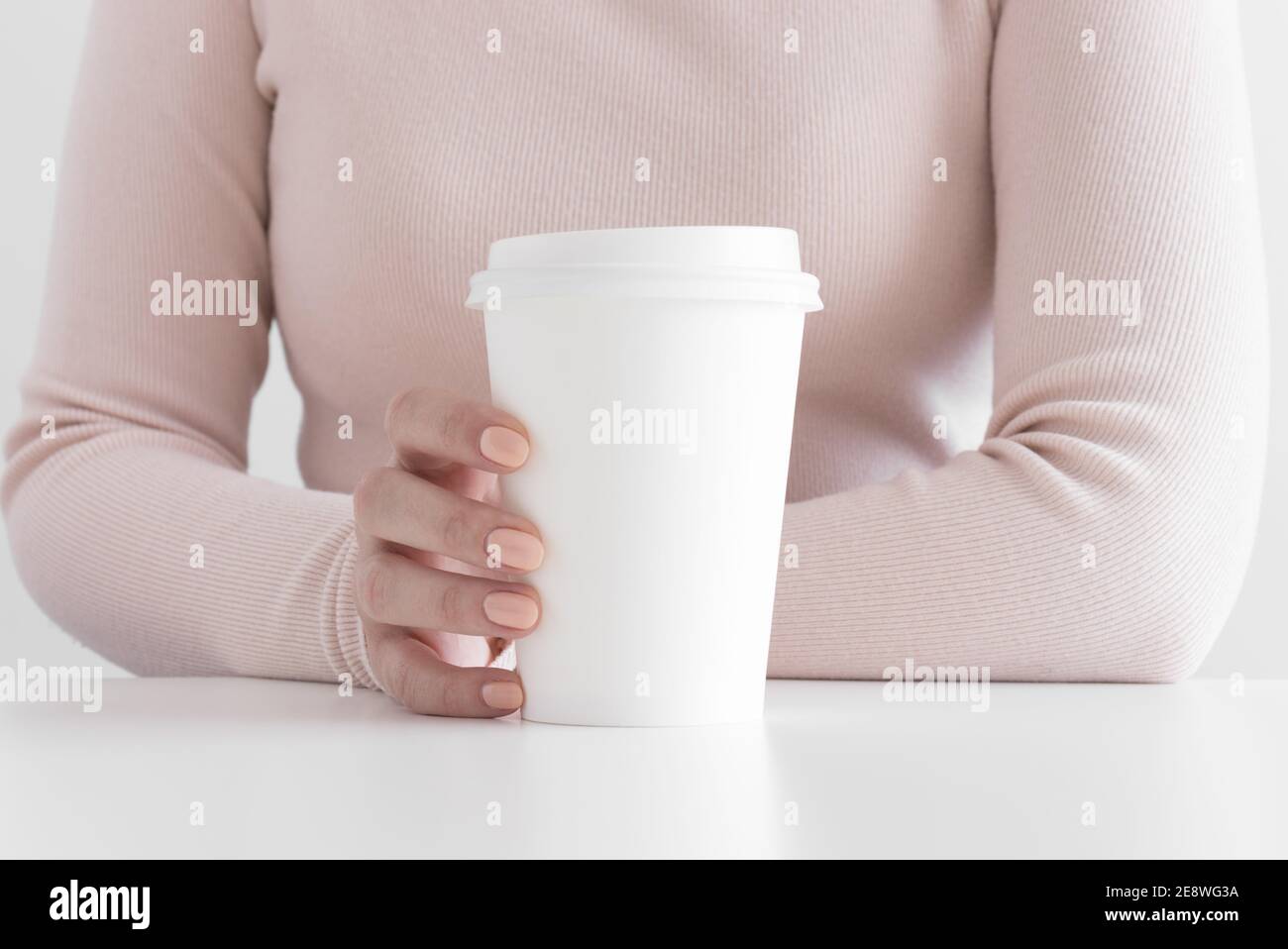 Donna che tiene il mockup bianco della tazza di carta del caffè. Foto Stock